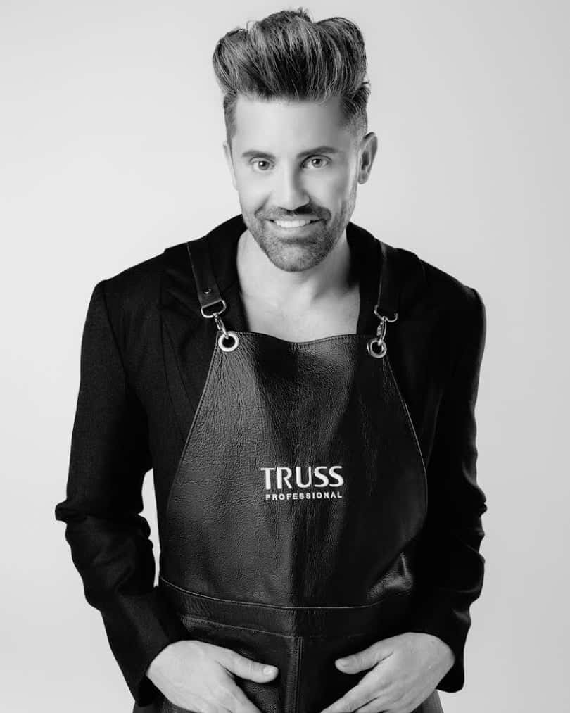 Gabriel Samra as Global Ambassador and Director of Stage Mastery for Truss Professional standing in truss hairstylist apron smiling