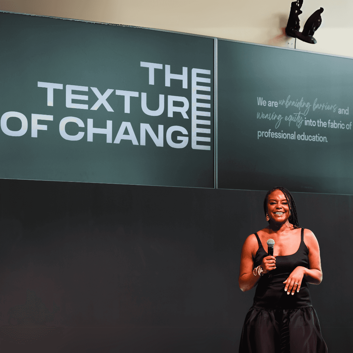 Speaker on stage at THE TEXTURE OF CHANGE™ with event mission displayed behind her