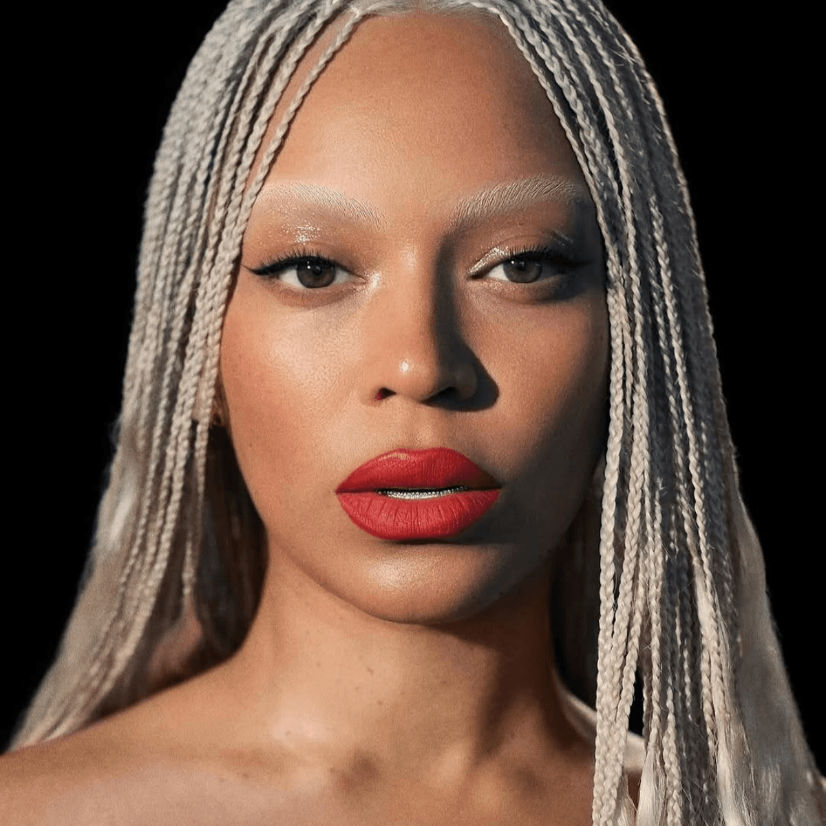 Close-up of Beyoncé with platinum braids, bold red lips, and striking bleached brows.