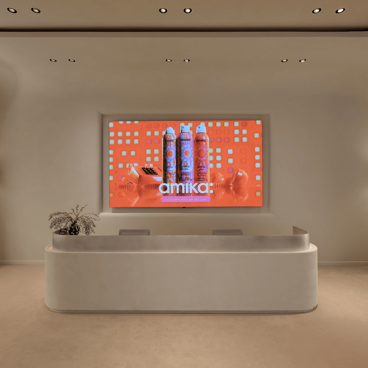 amika’s sleek lobby with a modern reception desk and digital brand display.