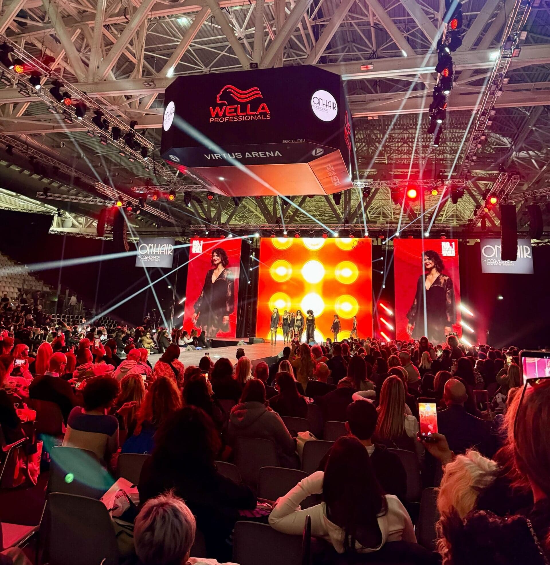 Wella Professionals hair show at Cosmoprof Bologna featuring runway presentation and large digital screens with vibrant lighting