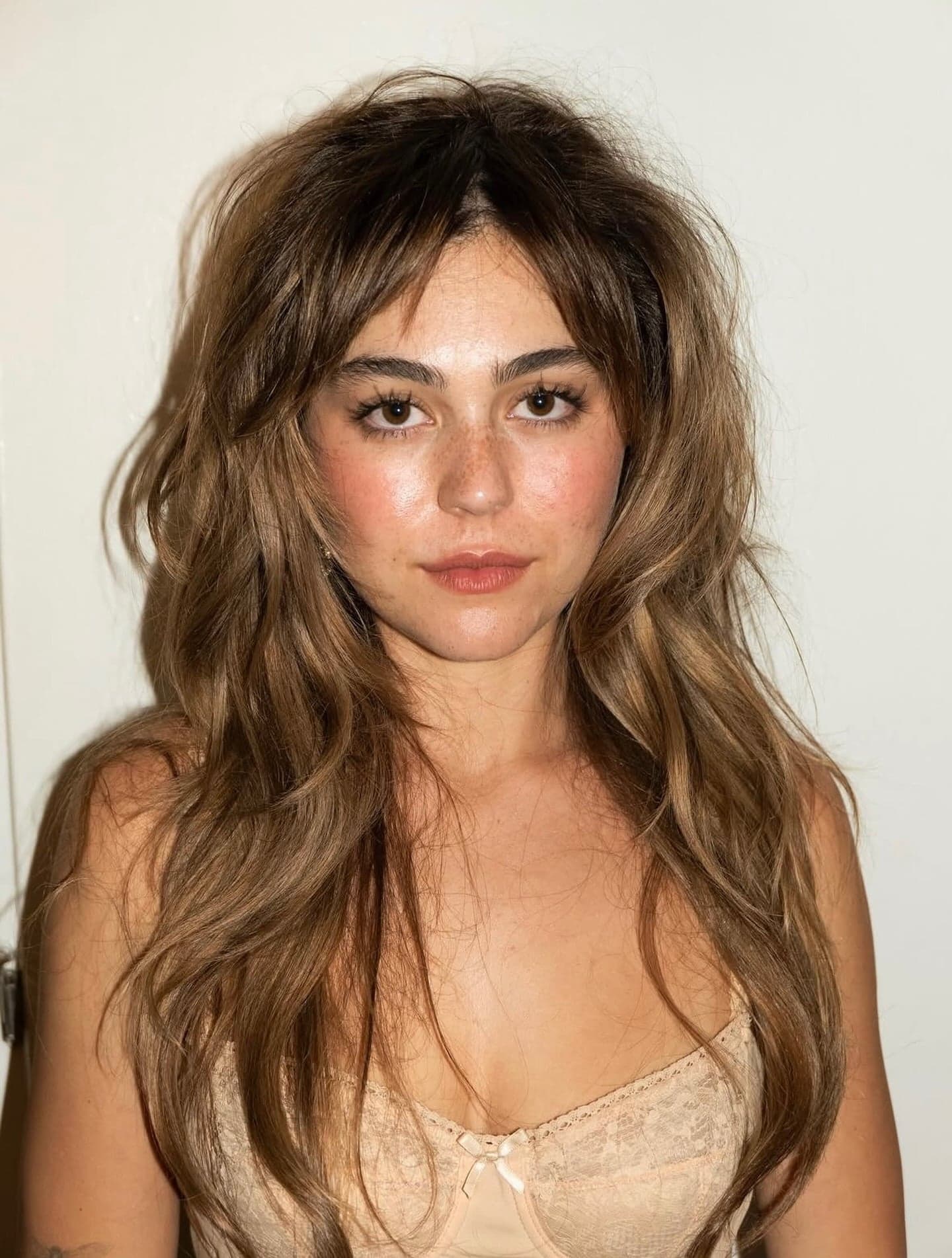 Mika Abdalla wearing a bronzed brown shag haircut with soft honey ribbon highlights, featuring textured layers, wispy fringe and dimensional brunette color.