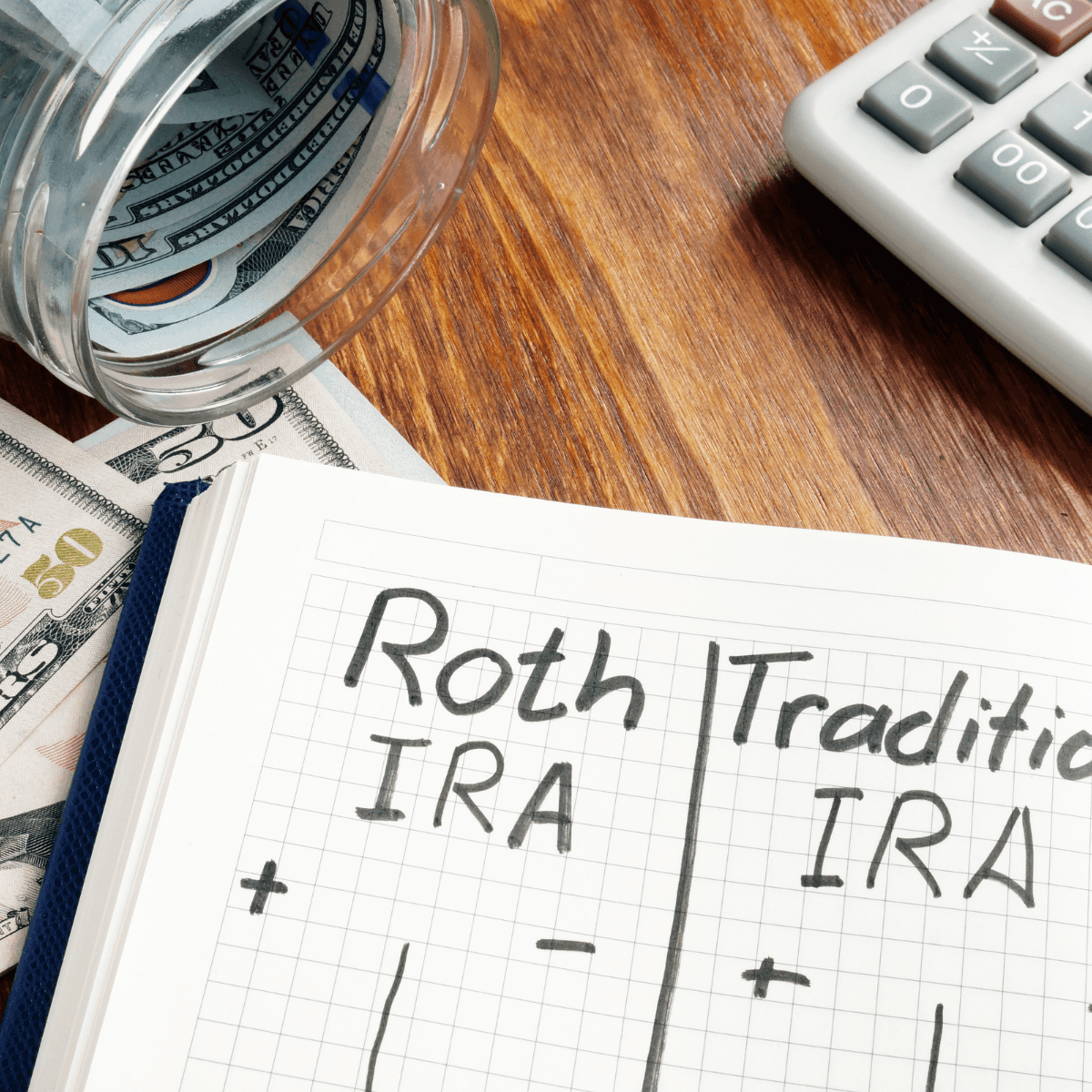 Notebook comparing Roth IRA vs. Traditional IRA with cash, calculator, and savings jar on desk for retirement planning.