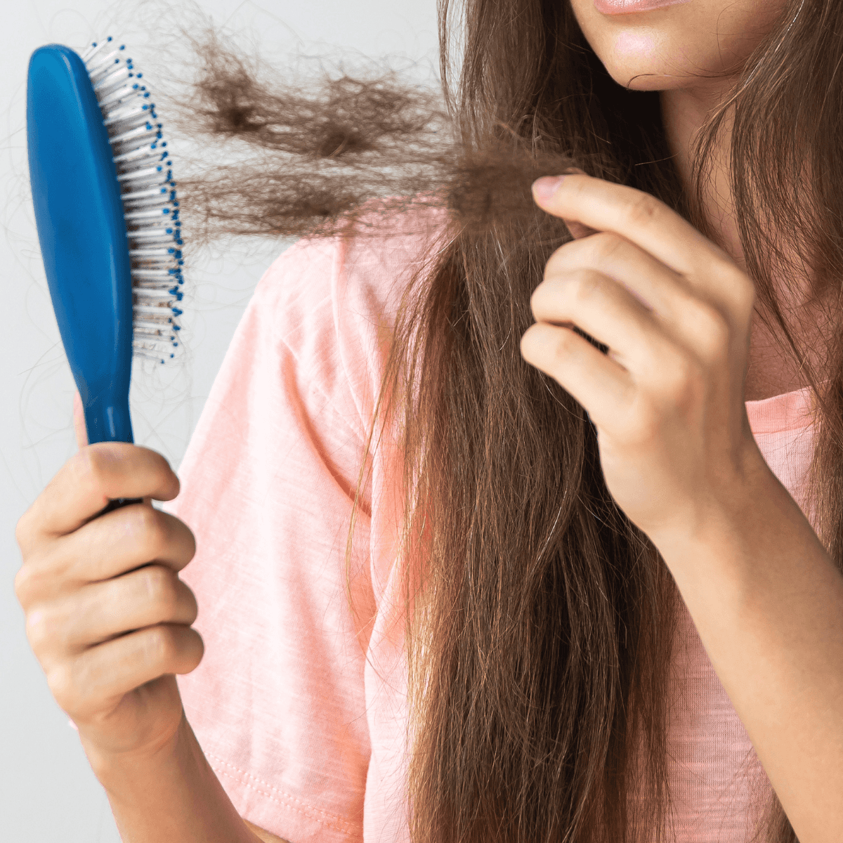 woman holding brush with hair on it shedding