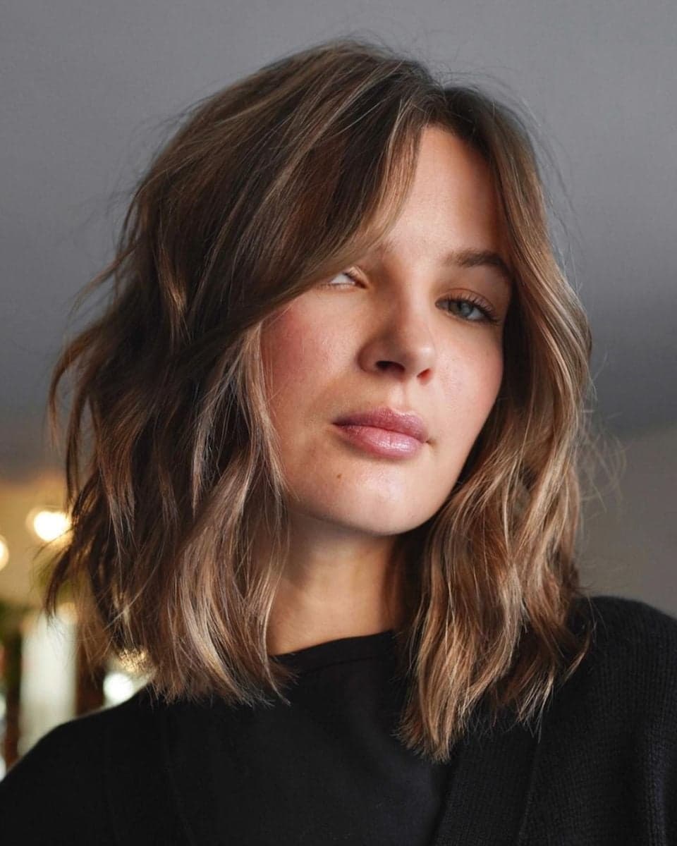 **Alt Text:** Model with a textured brunette lob, soft curtain bangs and dimensional blonde face-framing highlights, created by @yukistylist.