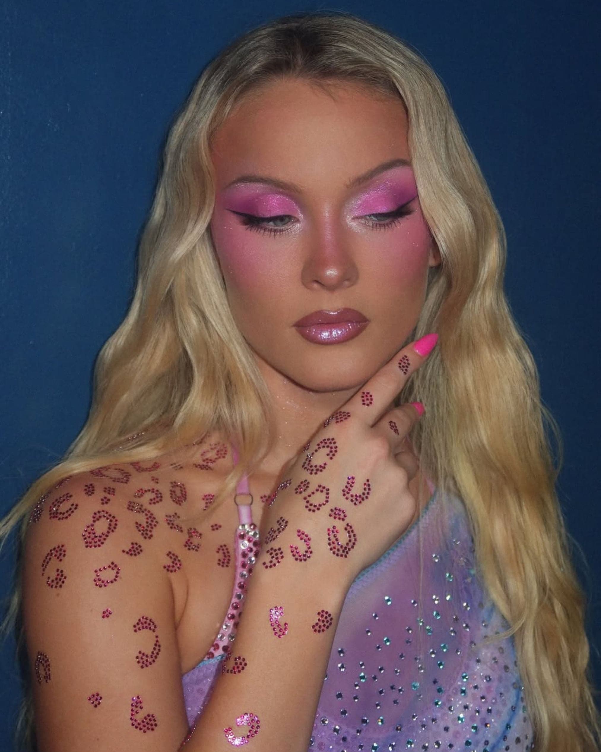 Model covered in pink rhinestone leopard-print body art paired with glittery pink eye makeup.