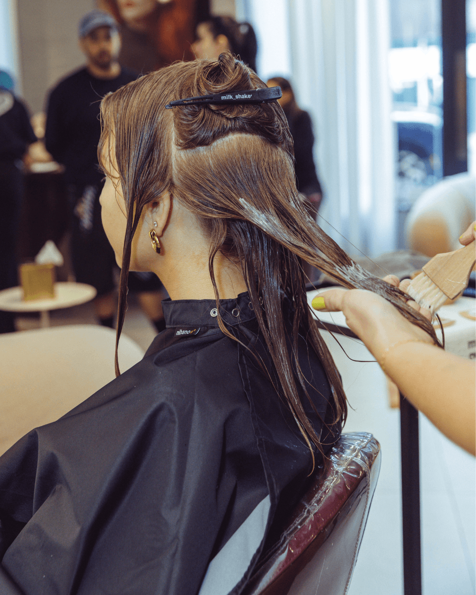 A milk_shake stylist applies Everlasting Bonds treatment to sectioned wet hair with a brush at Rob Peetom Salon.