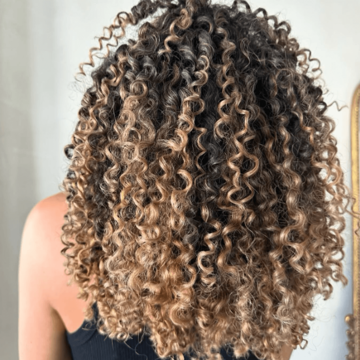 Warm, honey-toned bronde curls with rich depth and brightness.